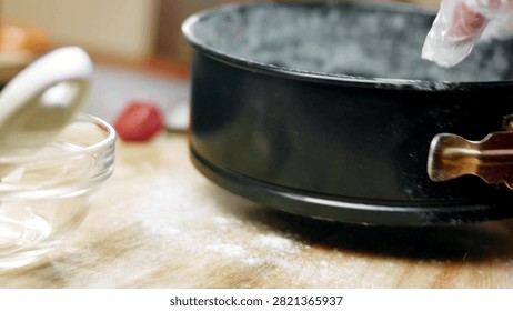 Gloved hand greasing the inside edge of a black springform pan