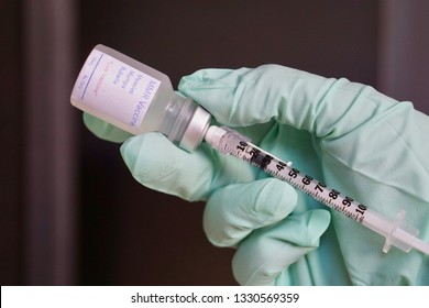 A Gloved Hand Holding A Needle Drawing Up The MMR Vaccine To Vaccinate Against Measles, Mumps, And Rubella As An Outbreak Occurs Across North America