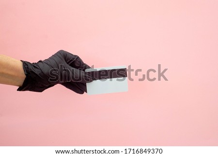 a gloved hand holds a card for contactless online payment of purchases.