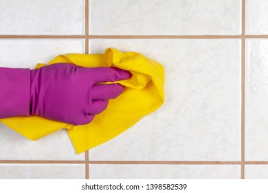 A Gloved Hand Holds A Rag And Washes Ceramic Tiles.