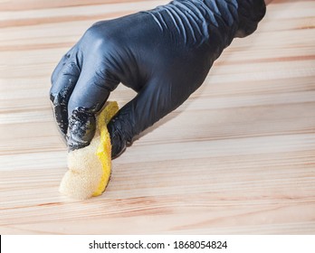 A Gloved Hand Paints A Wooden Table With Clear Varnish.