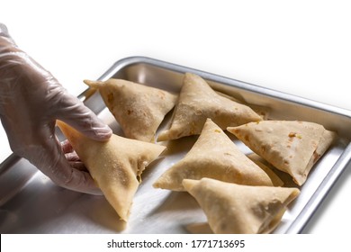 A Gloved Hand Placing A Fresh Samosa Wrap Before Taking It For Frying On A White Background