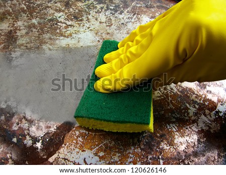 gloved hand scrubbing a dirty metal surface