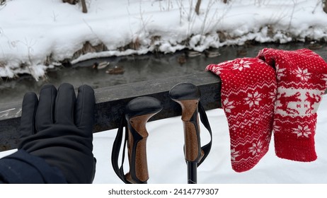 A gloved hand, sticks and mittens on the railing