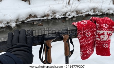 A gloved hand, sticks and mittens on the railing