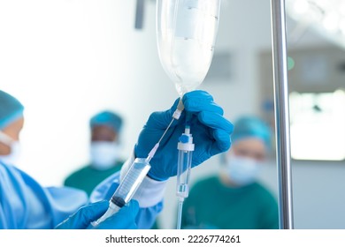 Gloved hand of surgical tech preparing iv fluid bag in operating theatre, with copy space. Hospital, medical and healthcare services. - Powered by Shutterstock