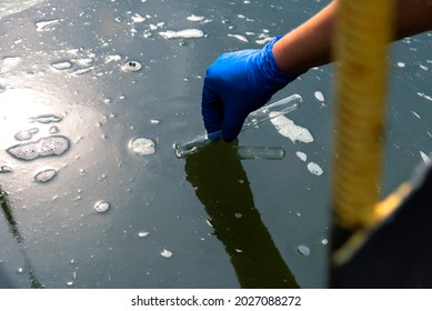 A Gloved Hand Takes Water Into A Test Tube From A City Reservoir. Urban Waste Water. Sampling From Open Water. Scientist Or Biologist Takes A Sample Of Water Into A Test Tube.