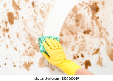 Gloved hand wiping clean a messy counter top or floor with a cloth or rag