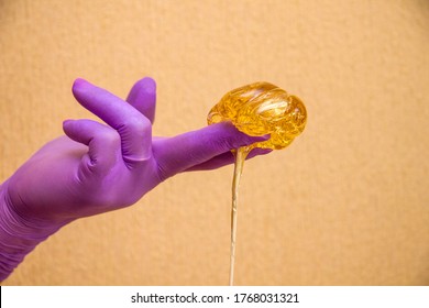 Gloved hands with flowing sugar paste for shugaring, depilation