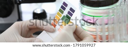 Gloved hands holding paper to test soil acidity. Litmus paper shows acidity, chemical analysis. Soil sampling for chemical analysis and ph test. Woman conducts chemical analysis fluid samples