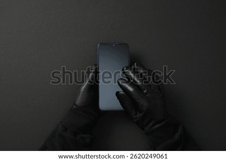 Gloved hands holding smartphone on dark background. Cyber security concept