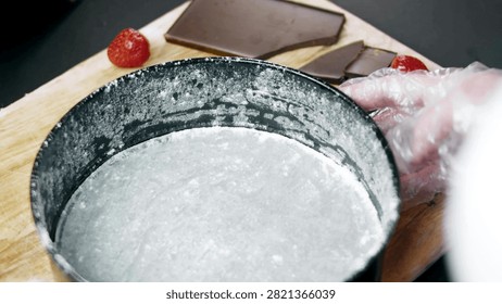 Gloved hands lining a round springform pan with parchment paper