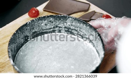 Gloved hands lining a round springform pan with parchment paper