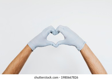 Gloved Hands Making A Heart Shaped Sign On A Gray Background