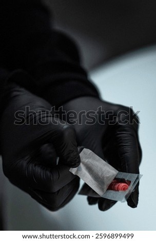 Gloved hands open a package containing a disposable needle
