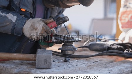 Gloved Hands Operating Angle Grinder On Steel, Closeup Capture Of Rotating Disc And Sparks, Dusty Bench Environment, Tactile Texture And Focused Manual Labor With Protective Clothing