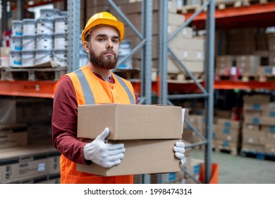 Gloved Man In Hardhat And Workwear Loading Boxes With Goods