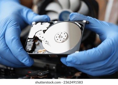 Gloved master holds computer hard drive. Computer equipment repair and maintenance concept