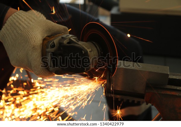 a gloved worker with a grinder cuts a\
carbide plate and this causes a lot of\
sparks