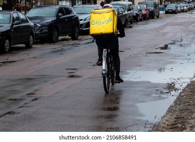 Glovo Delivery Service Courier Rides A Bicycle Along The City Street In Winter. Ukraine, Zhytomyr, January, 14, 2022