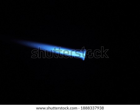 The glow of a gas lighter torch in the dark. Close-up.