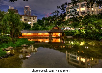 The Glow Of The Resting House Reflects Off The Pond In Hinokicho Park, A Japanese Water Garden In Tokyo Midtown, On A Summer Night