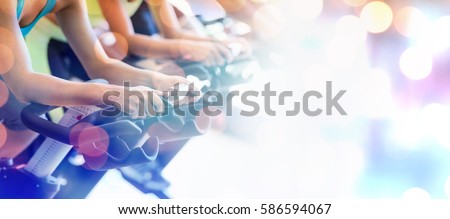 Glowing background against cropped image of people in spin class