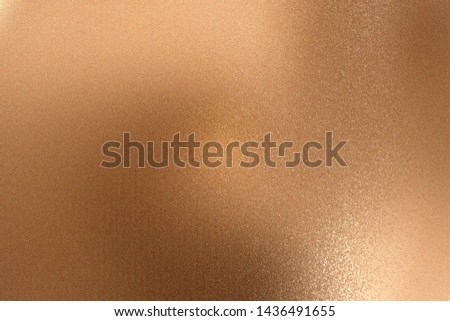 Glowing bronze metallic wall with scratched surface, abstract texture background