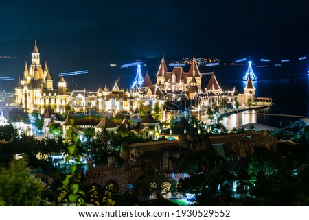 Glowing buildings in amusement park at night with funicular over sea