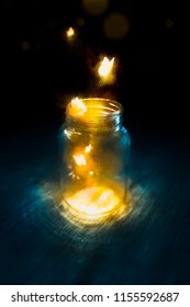 glowing butterflies flying out of a jar on a dark background