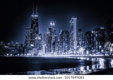 Glowing Chicago Skyline at Night. Iconic view of the Windy City's vibrant downtown from Lakefront Trail at North Avenue Beach along the Gold Coast. Blue stylized cityscape with copy space.