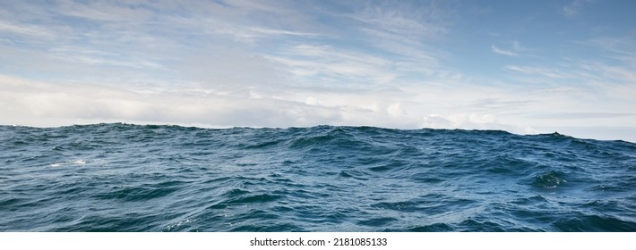 Glowing clouds above the sea. Waves, water splashes. Dramatic sky after the storm, epic seascape. A view from the yacht. Sailing in a rough weather. Nature, travel destinations, cruise