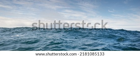 Glowing clouds above the sea. Waves, water splashes. Dramatic sky after the storm, epic seascape. A view from the yacht. Sailing in a rough weather. Nature, travel destinations, cruise