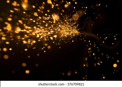 Glowing flow of steel metal welding spark dust particles shine in the sparkly dark background