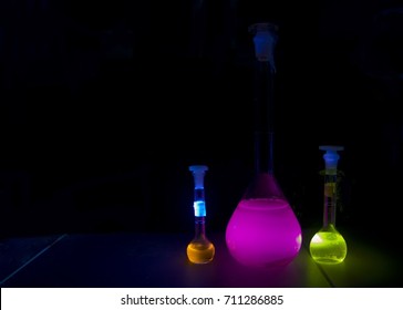 Glowing fluorescent flasks with samples - violet, orange and yellow
