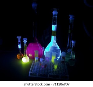 Glowing fluorescent flasks with samples - violet, blue, orange and yellow