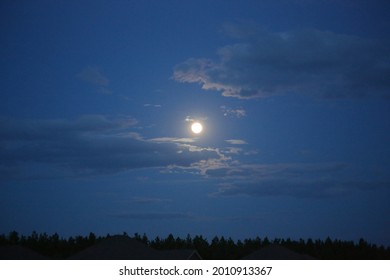 The glowing full moon up in the cloudy sky
