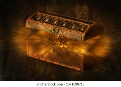 Glowing glitters splashing from an old, opened wooden dark brown treasure chest box, surprising gift concept 