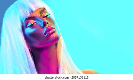 Glowing gold skin. Fashion model woman face in bright neon colourful lights, beautiful sexy woman with white hair and trendy make-up. Art design make up. Glittering, golden, metallic shine makeup