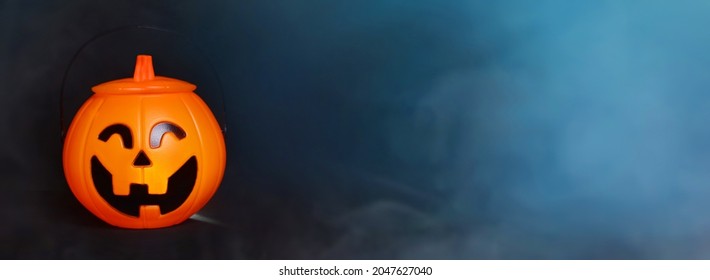 Glowing Halloween handbag in the form of a pumpkin on a background of blue smoke and fog.Halloween trick or treat!?opy space for text. Banner