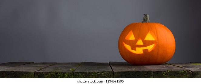 Glowing Halloween pumpkin head jack lantern on wooden table