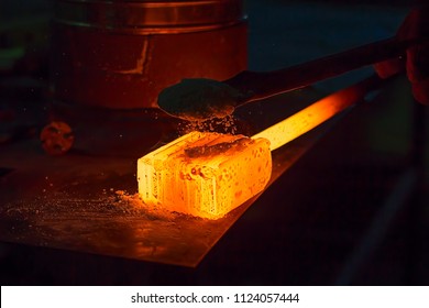 Glowing Iron Ingot On The Table. Hot Metal Workpiece For The Manufacture Of Damascus Steel.