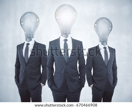 Glowing lamp headed businessmen on concrete background. Inovation concept 