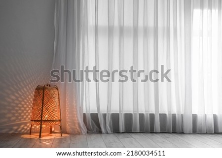 Glowing lamp near light curtain in room