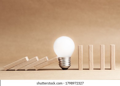 Glowing light bulb block the falling domino in a row to save the rest domino, problem and solution, creative idea to stop the collapse