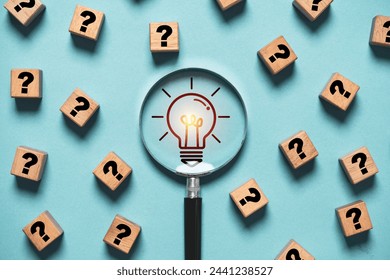 Glowing light bulb inside magnifier glass among question mark for focus and concentrate of creative thinking idea and problem solving concept.