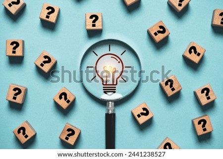 Glowing light bulb inside magnifier glass among question mark for focus and concentrate of creative thinking idea and problem solving concept.