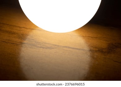 Glowing light bulb on a wooden surface. Shallow depth of field. - Powered by Shutterstock