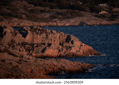 Glowing light red cliffs in the sunset and the blue Skagerrak ocean.