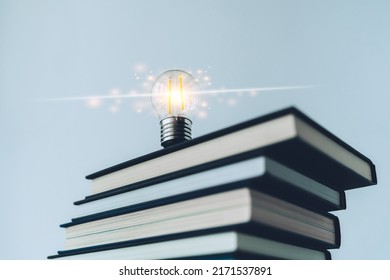 Glowing lightbulb or bright lamp with book or textbook. Skill improvement for student or businessperson. Studying and training course online at home. Business success idea, education learning concept - Shutterstock ID 2171537891